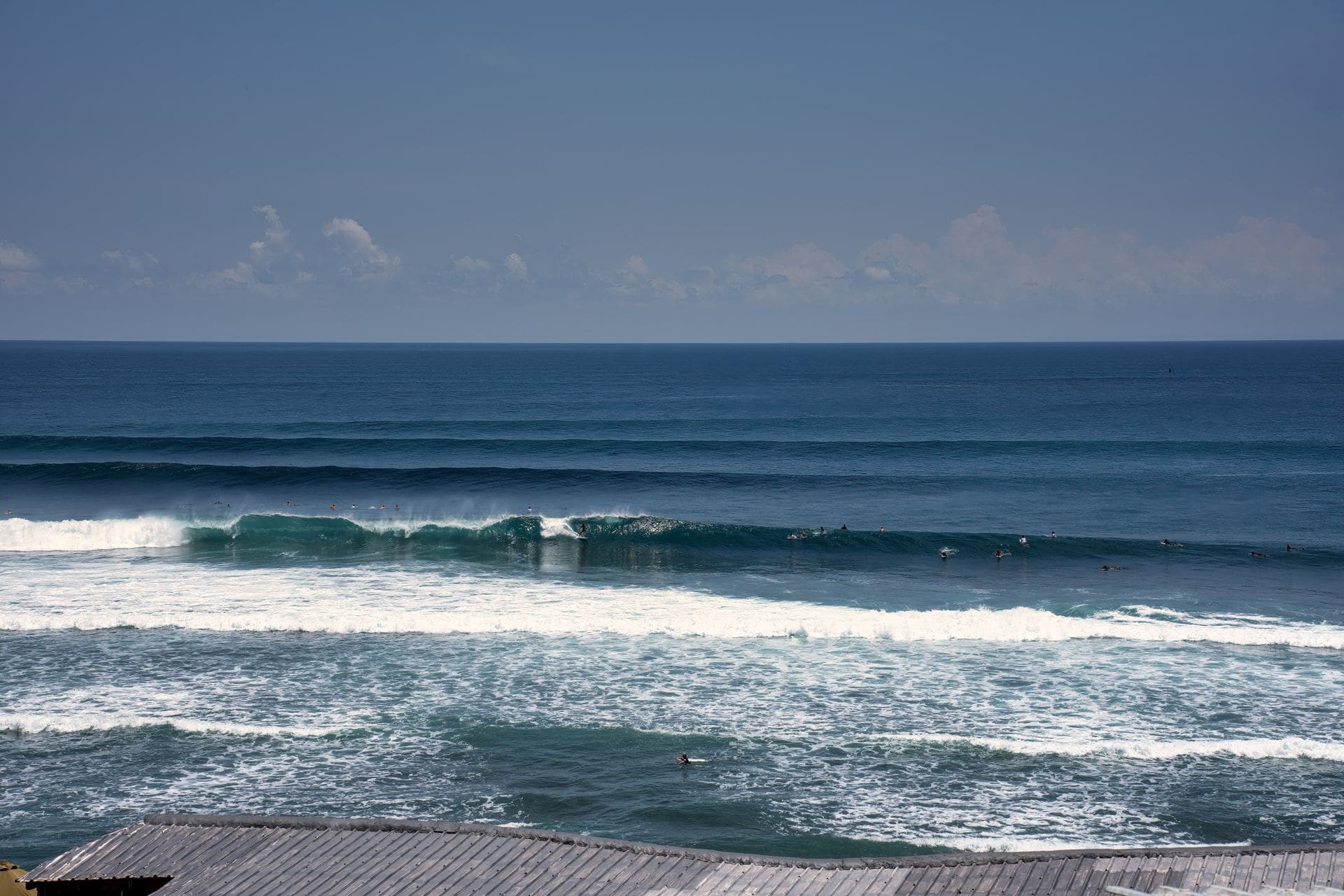 Surfistas cabalgando olas en un día soleado en Bali, Indonesia, con vistas al océano azul cristalino