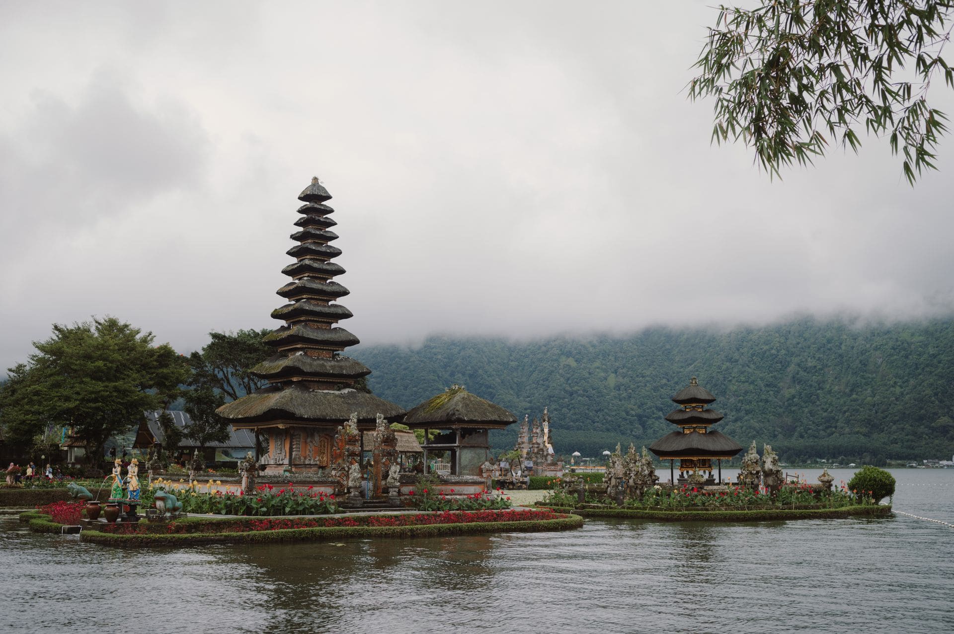 Sereno paisaje del templo Pura Ulun Danu Bratan junto al lago en Bali, con montañas brumosas al fondo