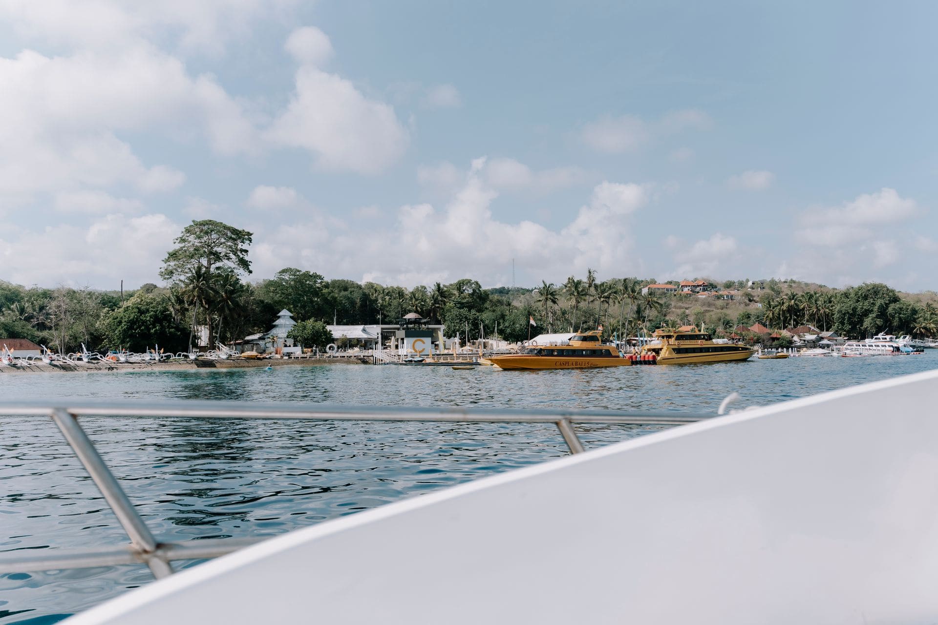 Explora un puerto tropical con barcos amarrados bajo un cielo azul despejado, fotografiado desde una embarcación