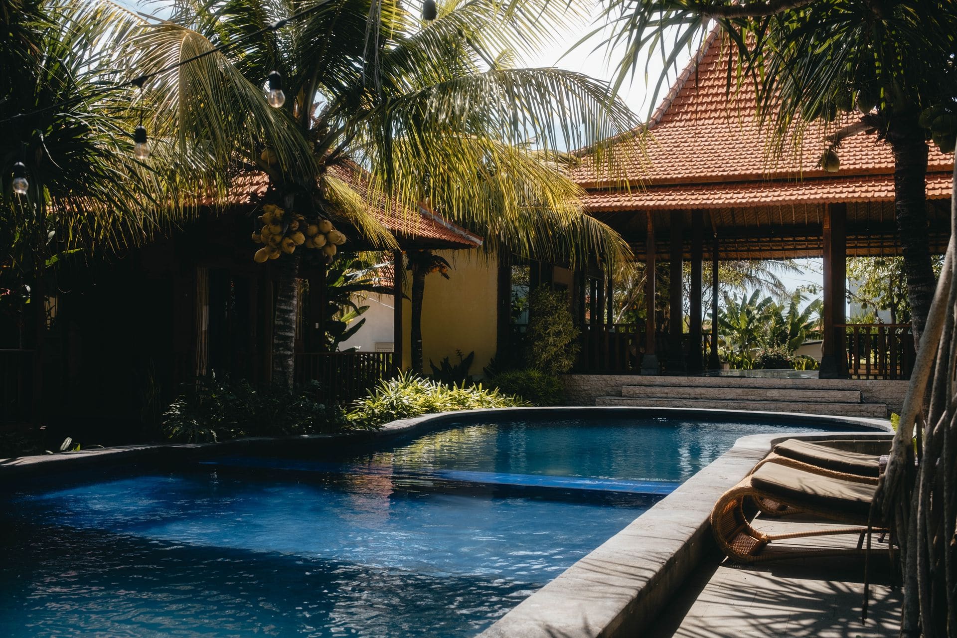 Relájate junto a una piscina tropical de lujo, rodeada de palmeras exuberantes bajo un cielo soleado, ideal para escapadas de verano