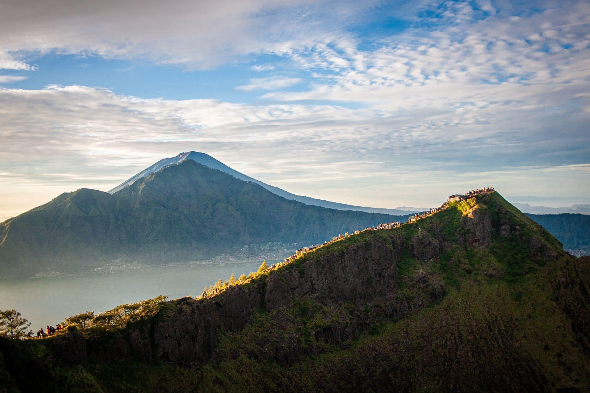 Hikers on the rim of Mount Batur watching the sun come up over a sea of cloud